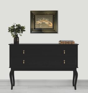 black dresser with decorative items and framed painting on white wall