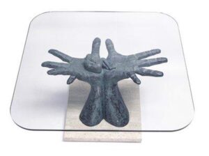 Glass table with two sculpted hands in a supportive position as the base