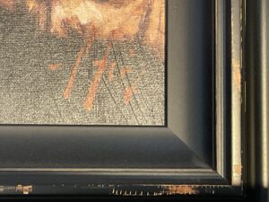 Close-up of black and brown framed artwork with visible texture and scratches