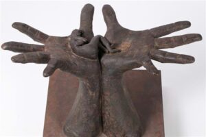 Bronze sculpture of two large hands holding a small reclining figure