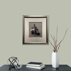 framed artwork of a ballerina displayed on a wall above a black tabletop with a vase and books