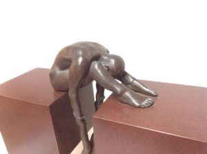 bronze sculpture of a man stretching between two platforms