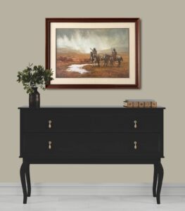 framed painting titled 'Spirit of the Rainmaker' by Howard Terpning displayed on a wall above a black console table with decorative items