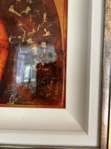 Close-up of a framed artwork corner featuring a signature by Kerry Darlington on a textured background with gold accents.