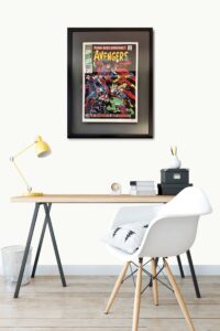 Framed comic book cover of 'Avengers king size special #2' by Stan Lee on a wall above a desk.