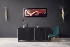 A modern living room featuring elegant decor with a framed artistic piece titled 'Sunrise in Florence' by Temper on the wall. A sleek black cabinet, a green cushioned chair, and decorative wall lights complement the ambient setting.