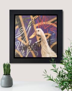 A framed artwork featuring a duck against a colorful graffiti backdrop titled 'Innocent' by artist Paul James.