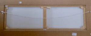 back view of framed artwork showing canvas and hanging wire