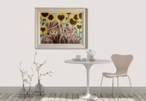 framed artwork titled 'Safe in the garden of love' by Jennifer Hogwood displayed on a wall above a round table and chair, with decorative branches in a vase nearby.