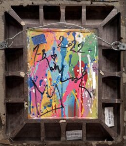 colorful abstract artwork with splashes of paint and scribbles on the back of a framed board