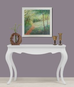 painting of a woodland path with trees and sunlight on a wall above a white console table