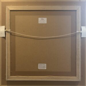 back view of a framed artwork showing its hanging mechanism and labels