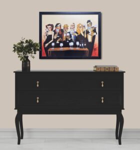 artwork titled 'Just a Taste' by Todd White hanging above a black drawer unit with a small plant and books