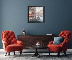 interior room with two red chairs, small round table, and framed Venice painting on blue wall